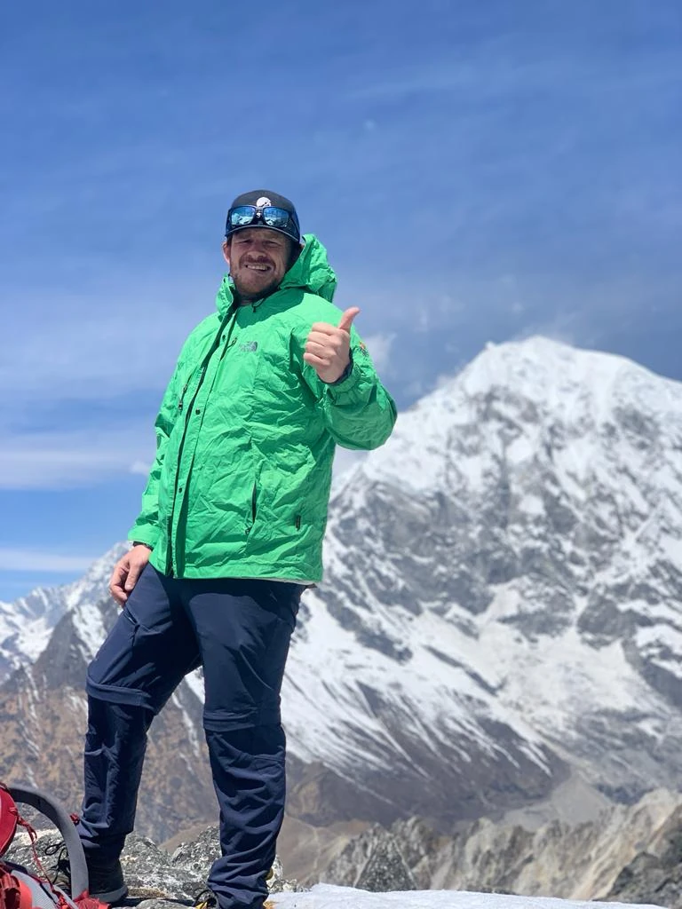 Alex McInnes on a Himalayan summit in Nepal, thumbs up